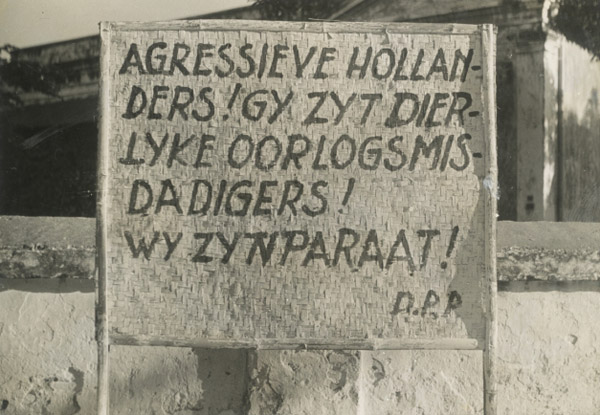 Foto van bord met tekst: Aggressieve Hollanders! Gy zyt dierlyke oorlogsmisdadigers! Wy zyn paraat! D.P.P.
