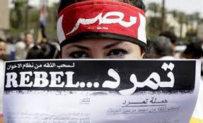 Foto van demonstrant die krant omhoog houdt met het woord Rebel