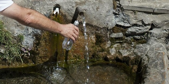 Foto hand vult fles met natuurlijk water