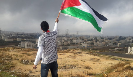 Palestijn met vlag, dorp op achtergrond